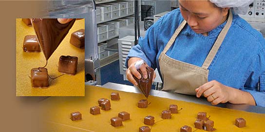 Photo of confections being enrobed with chocolate in an Alaska Wild Berry Candy Kitchen